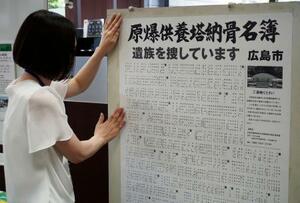 広島市役所で「原爆供養塔納骨名簿」のポスターを掲示する職員=11日午前