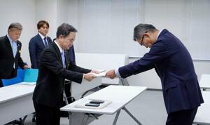 　防衛省沖縄防衛局の村井勝局長（右）に意見書を手渡す沖縄県宜野湾市議会の呉屋等議長＝２６日午後、嘉手納町