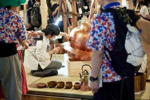 大阪・関西万博会場内の展示会で巨大なやかんに模様をつける職人