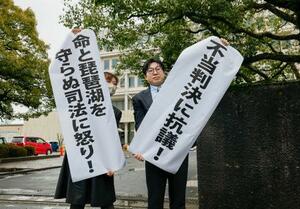 関西電力の原発計7基の運転差し止めを求めた訴訟の判決で、垂れ幕を掲げる原告側=25日午後2時3分、大津地裁前