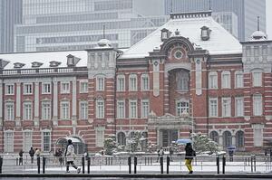 雪が降る中、ＪＲ東京駅前を訪れた人たち＝８日午前