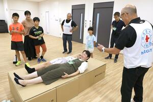 段ボールベッドを組み立て、寝転ぶ体験もした「親子で学ぶ夏休み防災イベント」=新潟市中央区