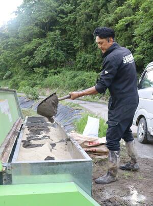 荒浜の砂を混ぜた肥料を田んぼにまく重野貴明さん=柏崎市北条