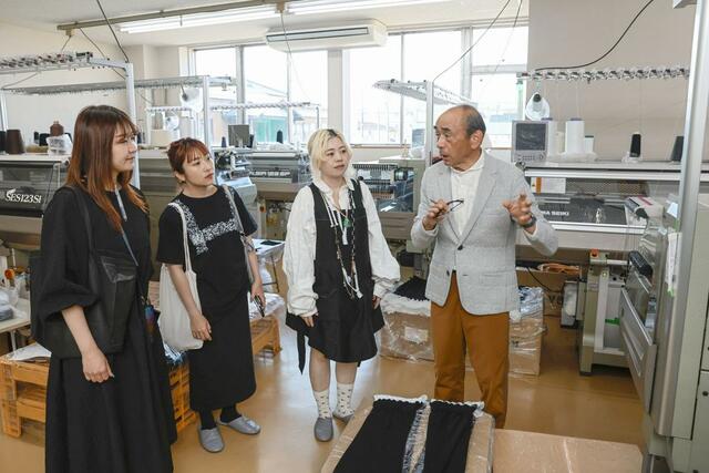 ウメダニットの工場で説明を受けるニットアーティストの蓮沼千紘さん（右から２人目）＝５月１４日、五泉市