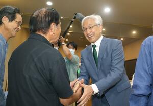 長岡市長選で3選を決め、支持者と握手する磯田達伸氏(右)=10月6日午後11時前、長岡市