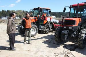 トラクターを前にする生産者たち。春の農作業が本格化する前に停戦合意となり、ひと安心をしていた＝８日、津南町