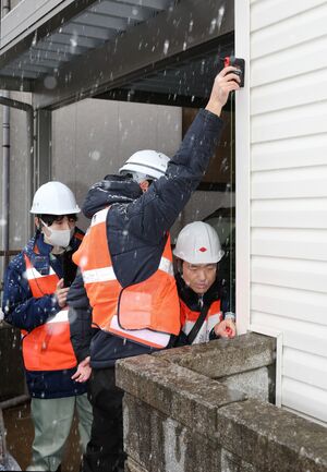 液状化による住宅の傾きを調べる新潟市職員ら=1月7日、新潟市西区