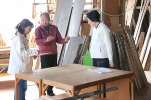 入校式後に工房で職人から説明を受ける桐たんす教室の受講生=田上町原ケ崎新田