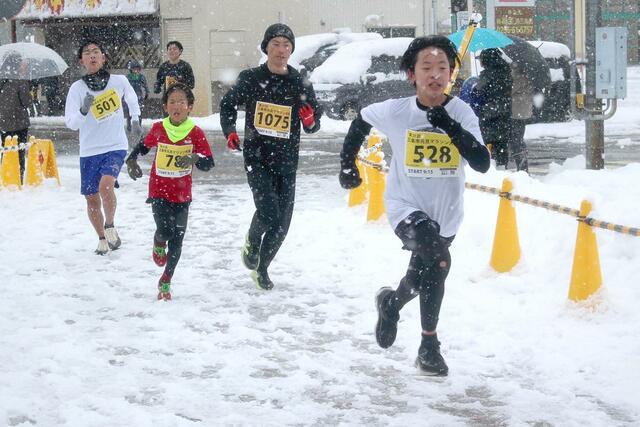 雪が降る中、懸命に駆けるランナーたち＝１月１日、三条市