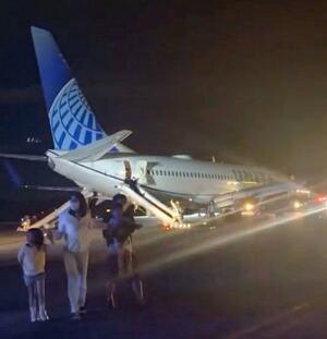 関西空港に緊急着陸したユナイテッド航空機から、脱出用シューターを使って避難する乗客ら=12日午後(乗客提供)