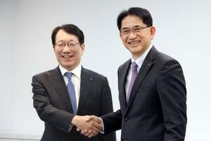 　三菱自動車の加藤隆雄社長（左）と握手する、次期社長就任が決まった岸浦恵介氏＝２２日午後、東京都港区