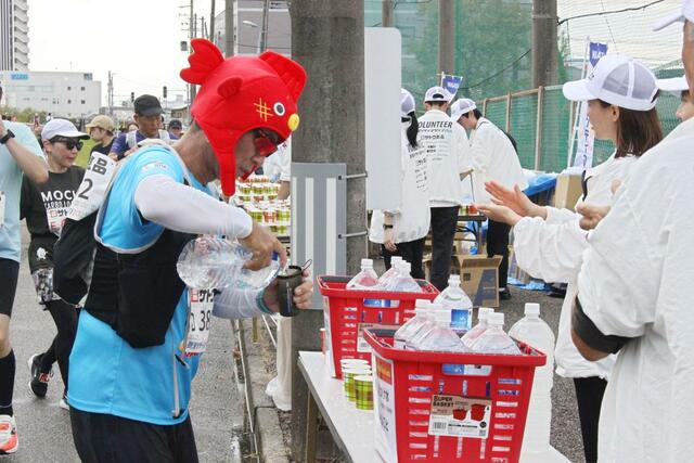 水が入ったペットボトルを手に取り、参加賞で配られたマイカップに給水する仮装ランナー＝12日、新潟市中央区