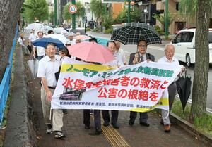 新潟水俣病第5次訴訟の審理再開を前に、横断幕を掲げ行進する原告団ら=7月8日、新潟市中央区学校町通1