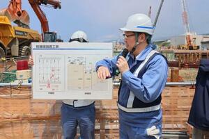 防潮堤の新設工事中について説明する北海道電力の世戸洋行・土木建築課長=1日午前、北海道泊村の泊原発敷地内