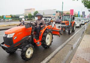 県内各地から集まった軽トラックとトラクターによるデモ行進=14日、長岡市