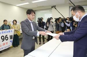 県民投票条例制定を直接請求する書類を県の担当者に提出した市民団体のメンバーら=3月27日、県庁