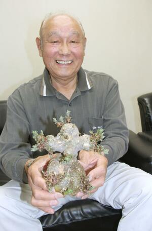 変わった形のジャガイモを持つ石井文夫さん=新発田市
