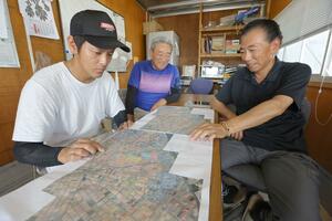管理する田んぼを示す地図を囲み、ほ場整備について話し合うエフ小杉の横野豊吉さん(右)ら=新潟市江南区小杉