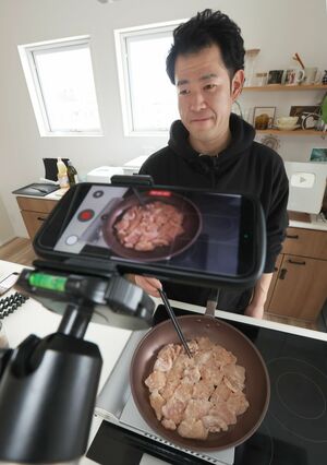 筋トレ飯を作る様子を撮影する羽賀裕也さん＝長岡市