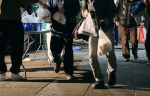 　屋外でＮＰＯ法人「ＴＥＮＯＨＡＳＩ」が用意した弁当などの食料品を受け取る人々＝１３日、東京・池袋