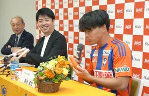会見でオイシックスの食品を試食する藤原奏哉選手(右)=ビッグスワン