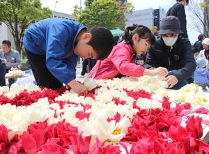 チューリップでの花絵作りを楽しむ親子連れら=4月21日、新潟市中央区