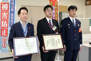 感謝状を受け取った、第四北越銀行三島支店の布施正彦支店長（左）とゆうちょ銀行日吉郵便局の山﨑俊明局長（中央）＝２１日、長岡市与板町与板