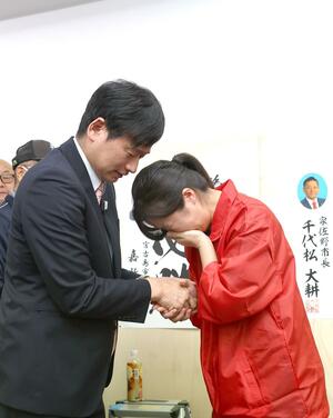 市長選で落選が決まり、陣営スタッフと握手する中川幹太市長(左)=26日、上越市五智新町