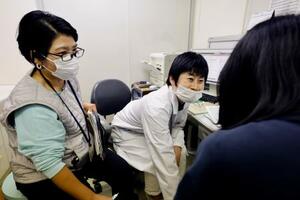 　通訳（左）を介しながら、ミャンマー出身の女性（右）を診察する高柳喜代子医師＝東京都千代田区の結核予防会総合健診推進センター