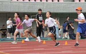 小学生に走り方を指導する久保倉里美さん(中央)=9月21日、新潟市中央区