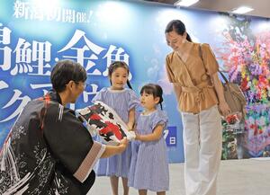 １万人達成のセレモニーで記念品を受け取る親子＝７日、新潟市中央区