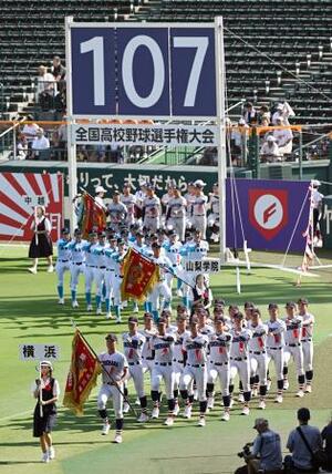 第107回全国高校野球選手権大会の開会式で、入場行進する横浜(手前)の選手ら。厳しい暑さへの対策として初めて夕方から実施された=5日、甲子園球場