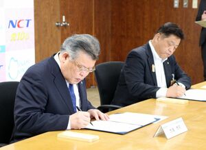 協定書に署名するトップライズの大滝充司社長(手前)と林茂男南魚沼市長=5月13日、南魚沼市役所