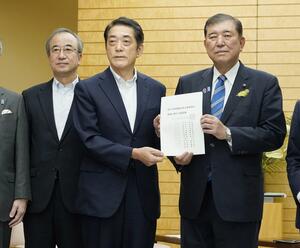 石破首相(右)に原子力発電関係団体協議会の要請書を手渡す会長の中村時広愛媛県知事。左は新潟県の花角英世知事=27日、首相官邸