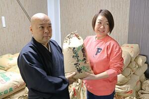 県フードバンク連絡協議会の山下浩子会長(右)にコメを手渡す近藤真弘住職=三条市南四日町2