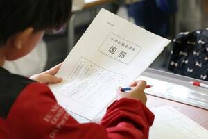 　全国学力テストで問題用紙を手に開始を待つ児童＝２３日午前、東京都内の小学校（代表撮影）