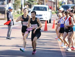 新潟北・teamTOMOZO(A)の4走篠澤葉選手(左)からアンカー高山花帆選手にたすきをつないだ第4中継所=11月4日、長岡市学校町1