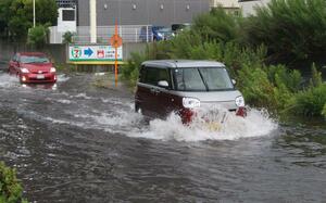 大雨で道路が冠水し、水しぶきを上げて進む車＝７月２５日午前１０時前、新潟市中央区上所（画像を一部加工しています）