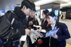 モバイルバッテリーの取り扱い変更を利用客にチラシで周知する航空会社の関係者=4月、羽田空港