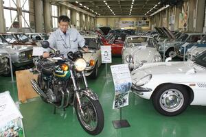 所狭しと並ぶバイクやクラシックカー。松井義敬さんが手をかけるバイクや一部の車は、エンジンを起動して音と振動を体感できる=三条市上須頃