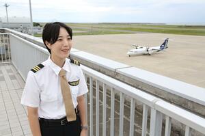 真新しい女性パイロットの制服に身を包み、抱負を語る安部美咲さん=新潟市東区の新潟空港
