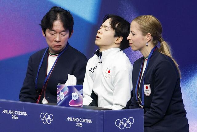 男子フリーの得点を確認し、目を閉じる鍵山優真。左は父の正和コーチ、右はカロリナ・コストナー・コーチ＝ミラノ（共同）