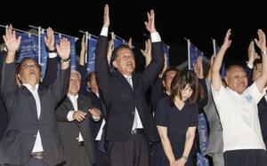 茨城県東海村長選で4選を果たし、万歳する山田修氏(中央)=7日午後、茨城県東海村