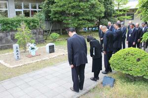 新潟市水道局職員が２００７年に自殺した問題で、水道局の中庭に植樹された木に黙とうする遺族（左から２人目）と水道局幹部職員＝８日、新潟市中央区関屋下川原町１