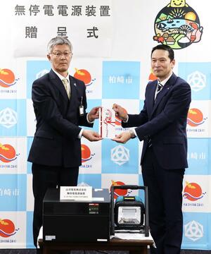 柏崎市に災害時に活用する無停電電源装置を寄付した「品田電業社」の品田史夫社長(右)=柏崎市役所
