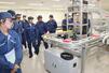 小川コンベヤで搬送システムなどを見学する長岡工業高専の学生たち=長岡市滝谷町