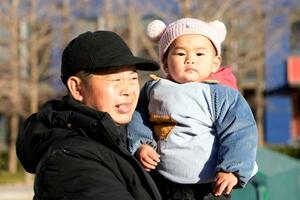 北京市内の公園で祖父に抱かれた子ども=2025年12月(共同)