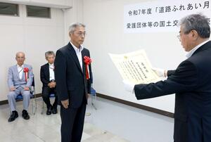 国土交通大臣表彰の感謝状を受ける越沢自治会総代の石割治さん(中央)=村上市田端町