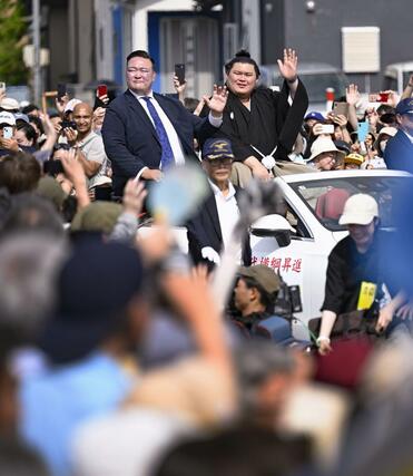 石川県津幡町で行われた大相撲の横綱昇進を祝うパレードで、沿道に集まった人たちの声援に応える大の里関。左は二所ノ関親方＝２９日午後