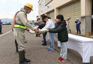 除雪出動式で除雪業者に激励のメッセージを手渡す児童=上越市